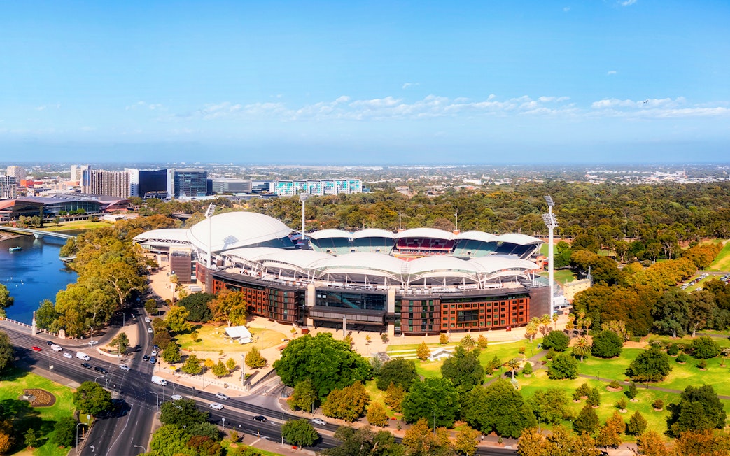 Aerial view of Adelaide Oval surrounded by parklands and cityscape.