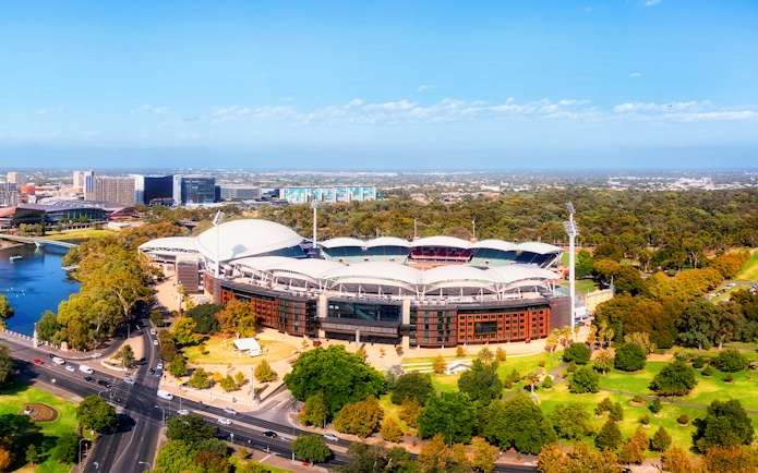 Aerial view of Adelaide Oval surrounded by parklands and cityscape.