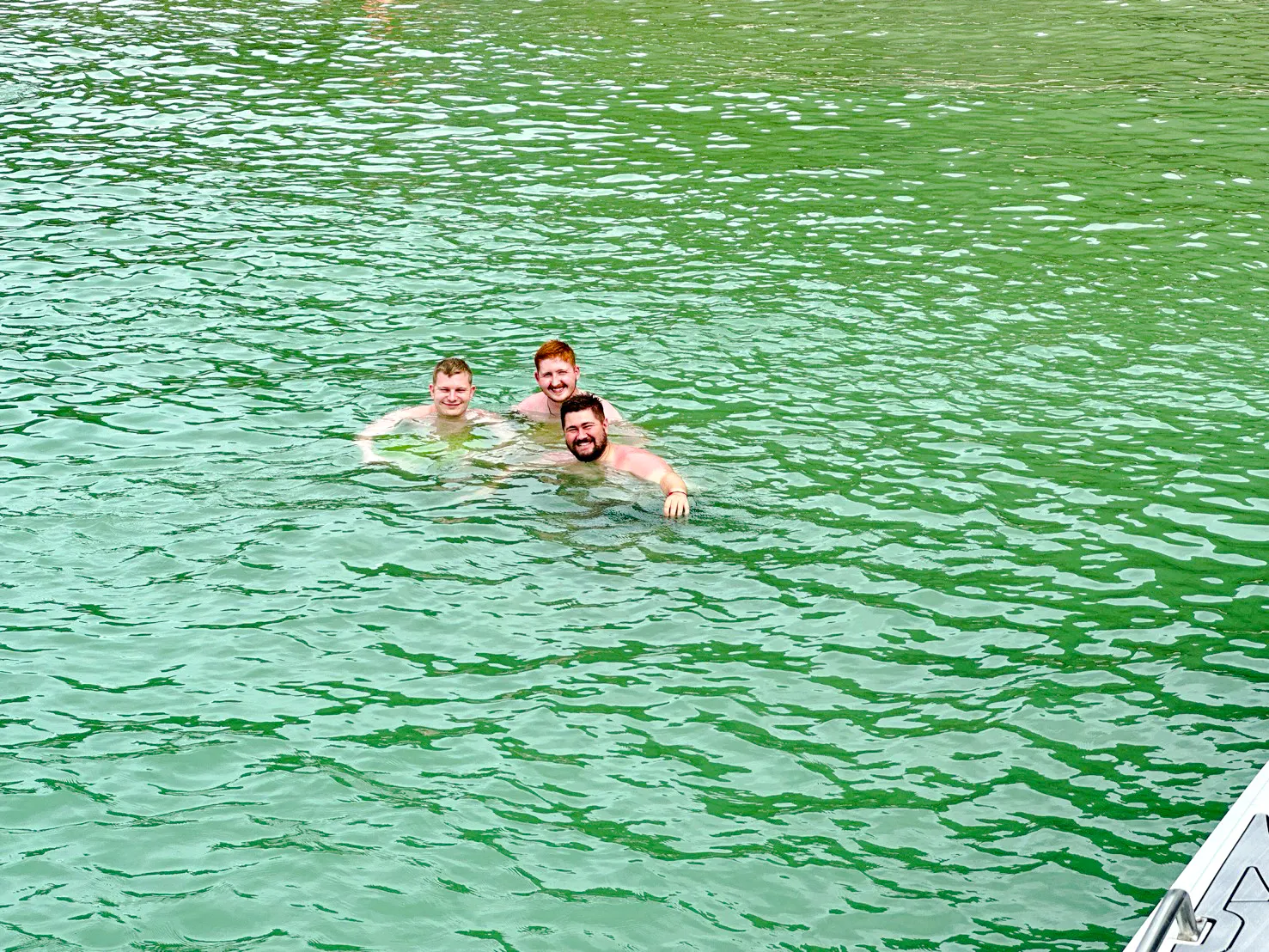 Three people swimming in the clear waters of Anthong Marine Park during an island hopping adventure.