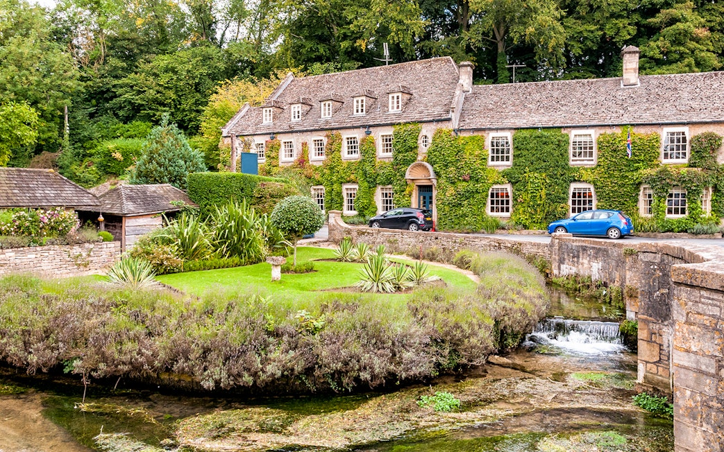 Cotswolds stone house with ivy, garden, and stream on a London day tour.
