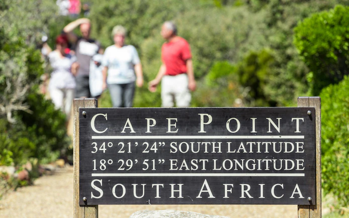 Cape Point sign with coordinates, South Africa pathway in background.