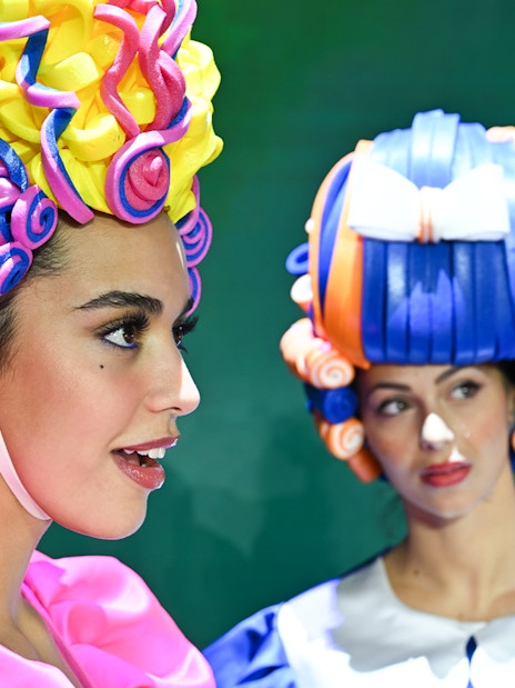 Performers in colorful wigs at Paris cabaret show.