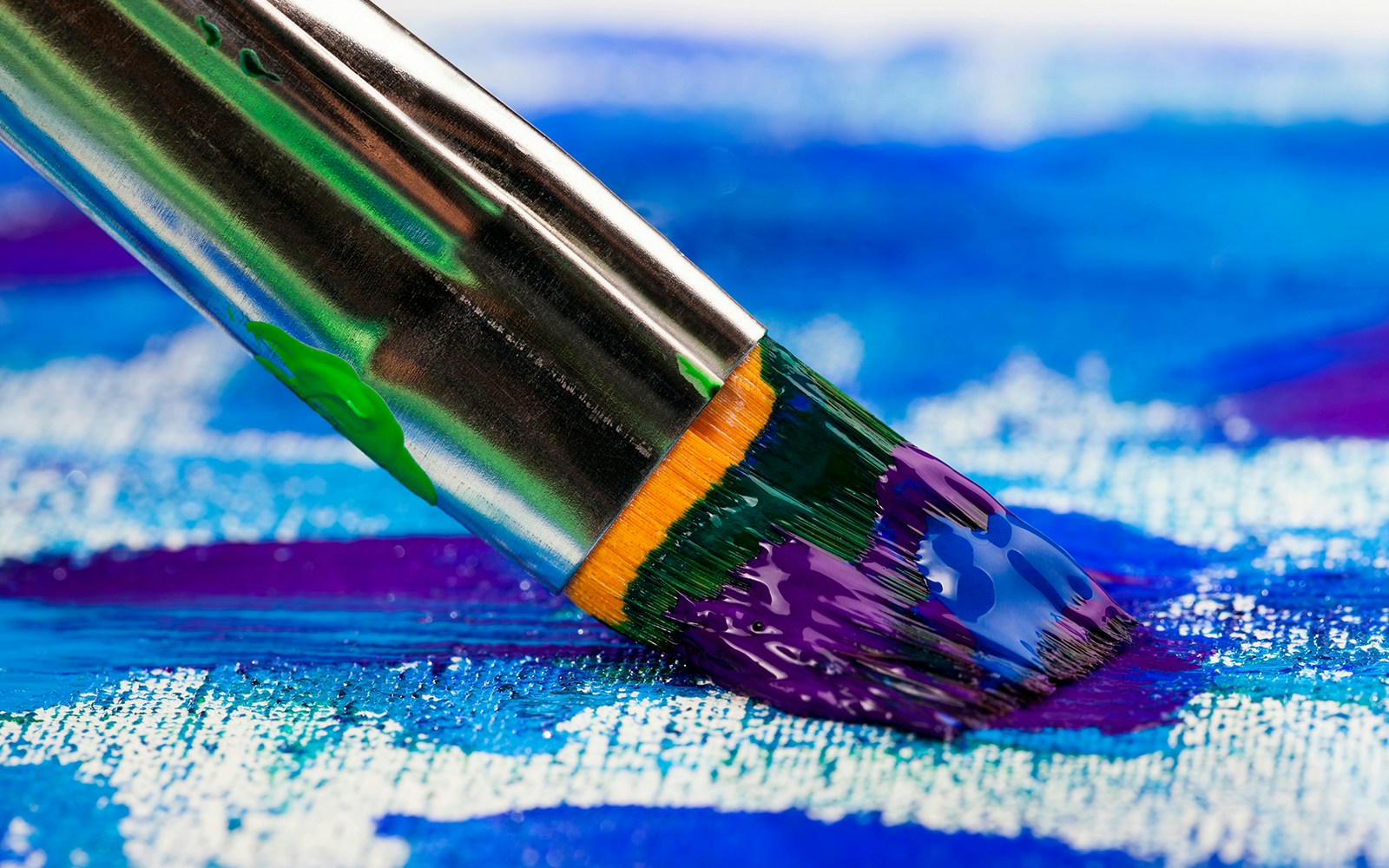 Closeup of a paintbrush applying vibrant colors on a canvas.
