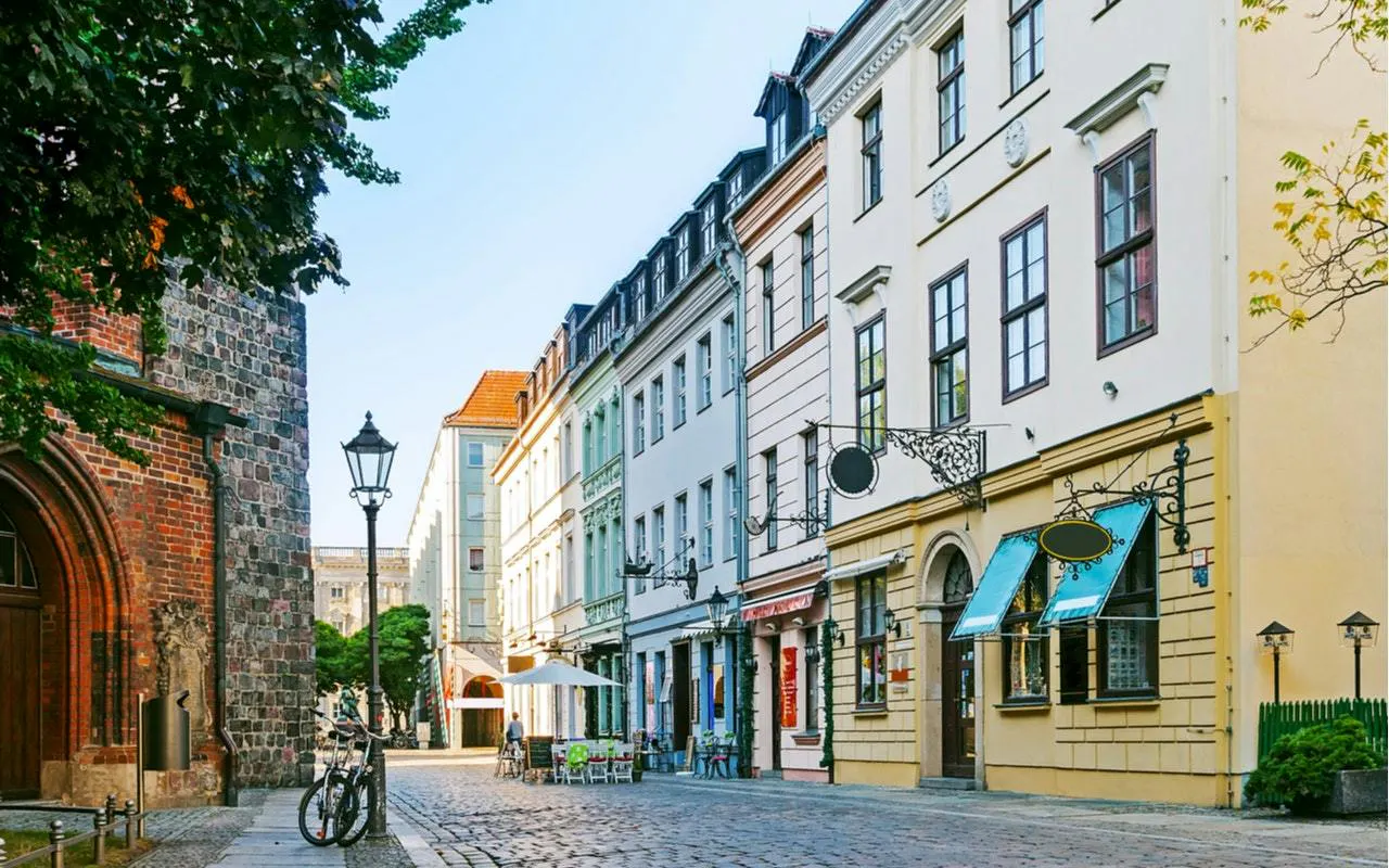Cobblestone street in Berlin Kreuzberg with historic buildings and outdoor cafes.
