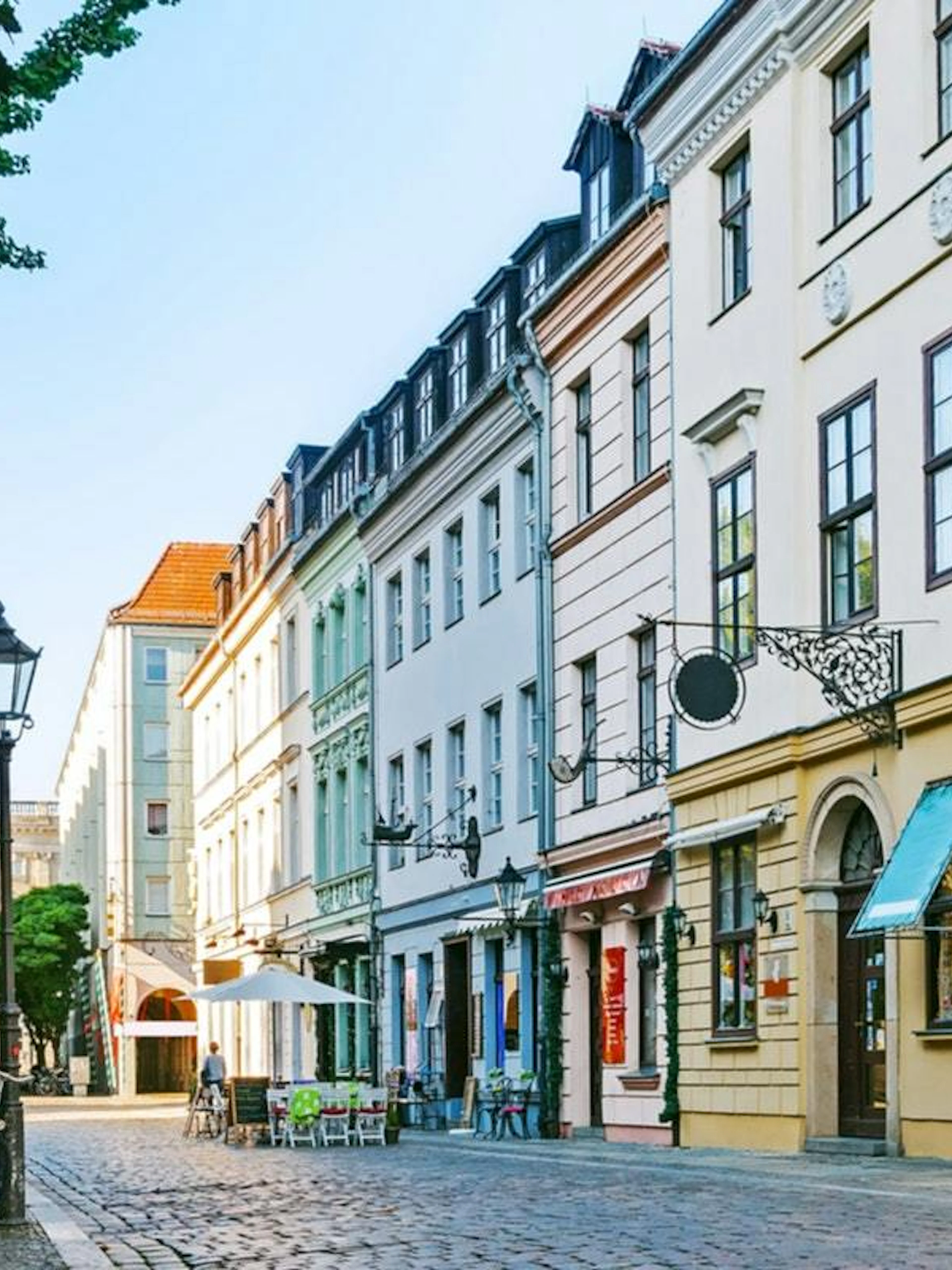 Cobblestone street in Berlin Kreuzberg with historic buildings and outdoor cafes.