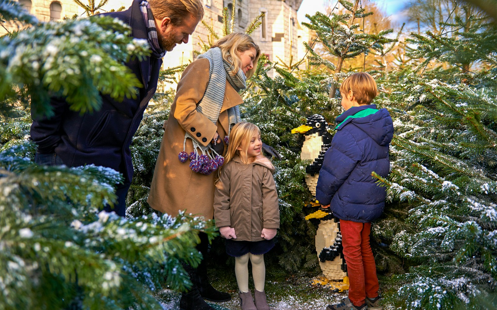 Family exploring Lego penguin display at Legoland Christmas, London.