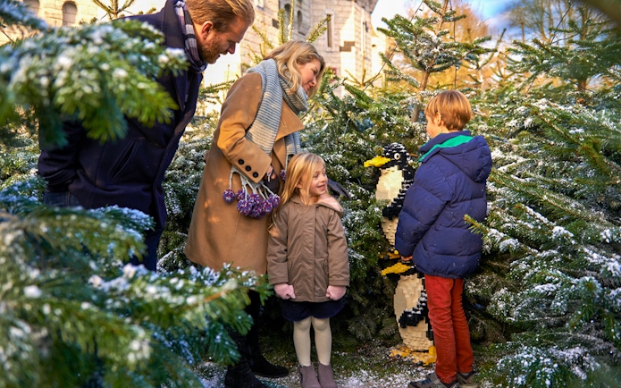 Family exploring Lego penguin display at Legoland Christmas, London.