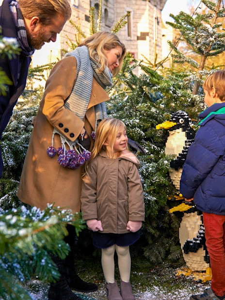 Family exploring Lego penguin display at Legoland Christmas, London.