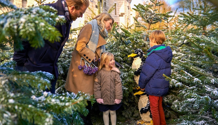 Family exploring Lego penguin display at Legoland Christmas, London.