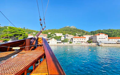 Karaka ship approaching Elaphite Islands with coastal village view.