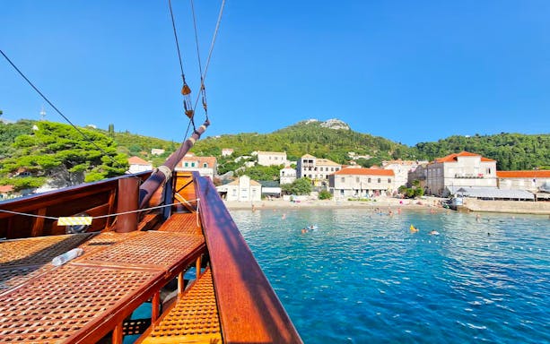 Karaka ship approaching Elaphite Islands with coastal village view.