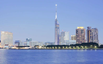 Fukuoka Tower illuminated at dusk with city skyline and waterfront.