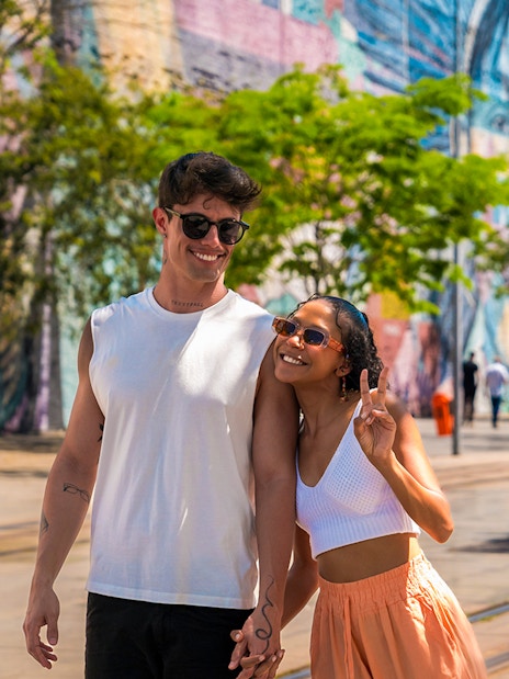 Tourists walking along Olympic Boulevard with colorful mural in the background.
