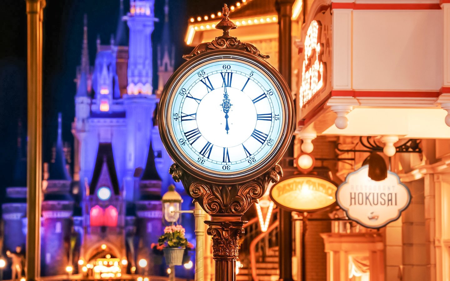 Clock tower in World Bazaar area at Tokyo Disneyland with illuminated castle in background.