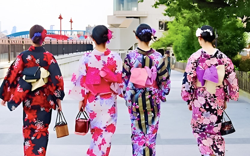 Women in colorful kimonos walking along a path in Tokyo, Japan.