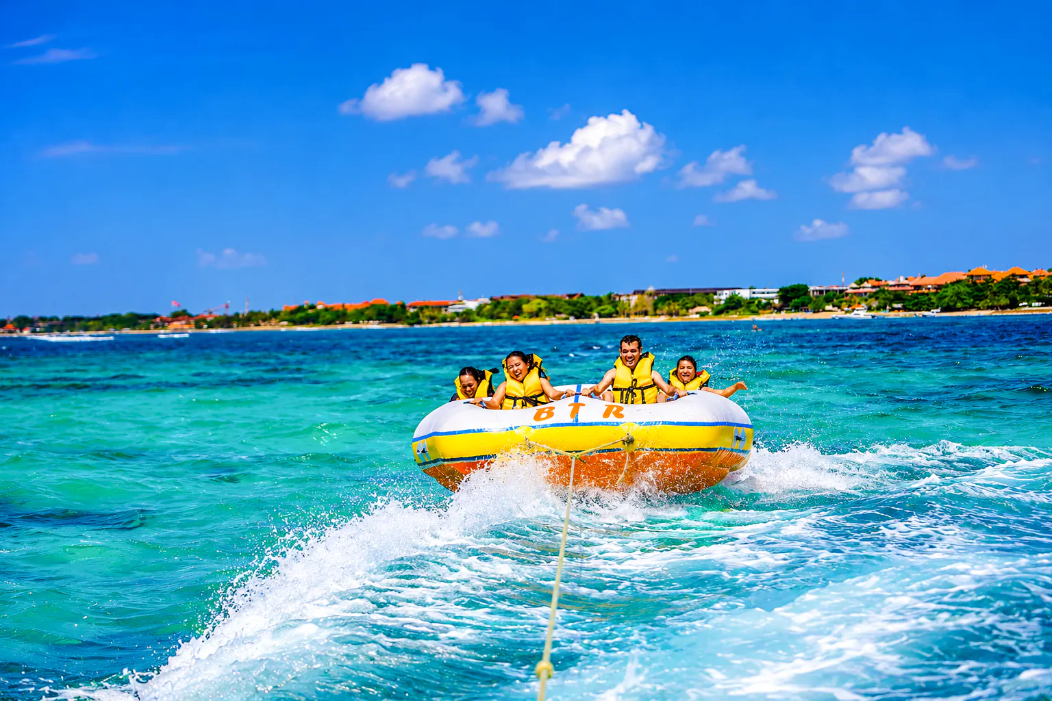Tubing adventure at Tanjung Benoa, Bali with tourists enjoying ocean watersports.