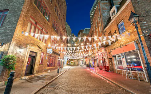 Cobblestone street in New York City lit by string lights, part of Alexander Hamilton self-guided tour.