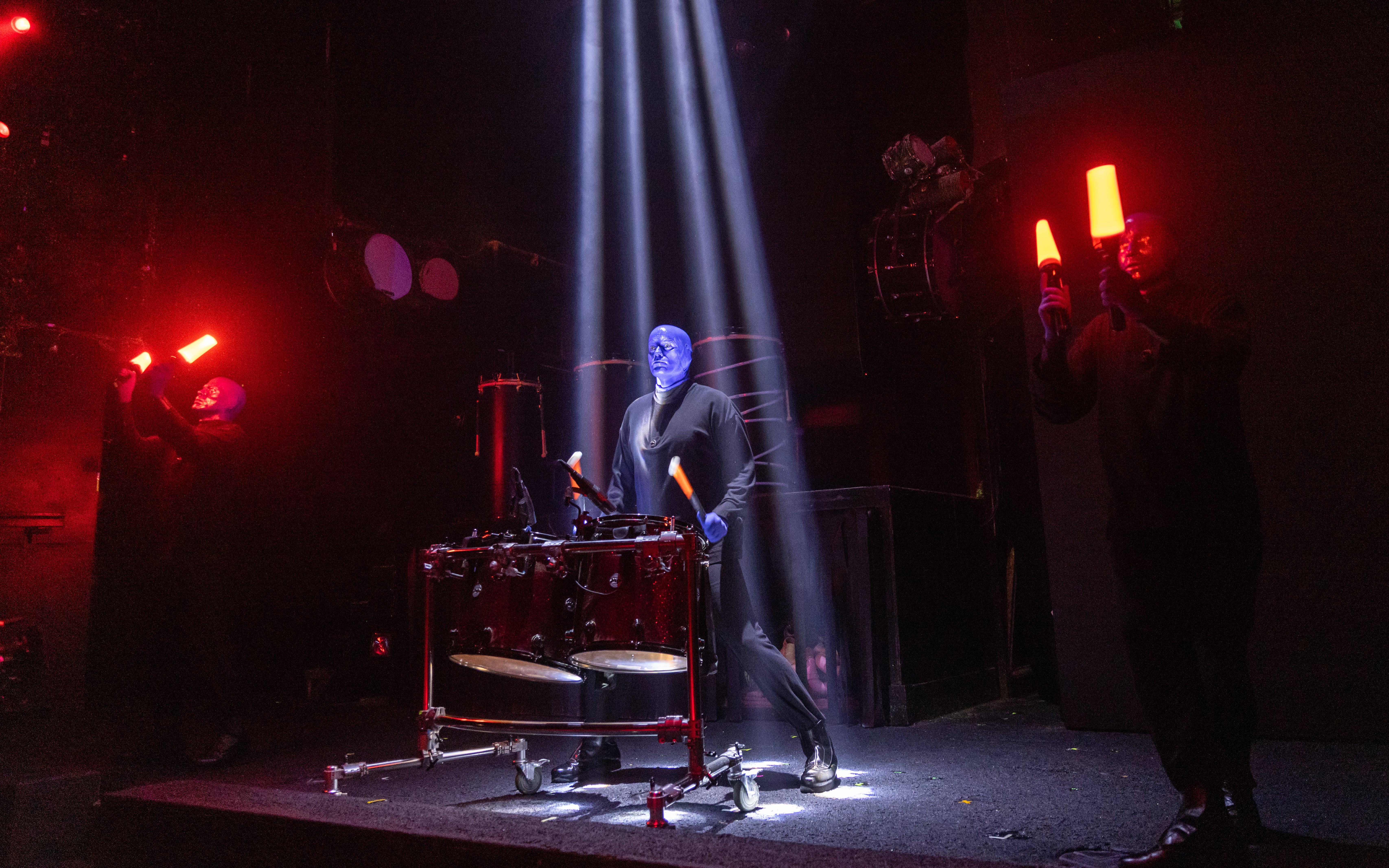 Blue Man Group performing with drums and glowing sticks on stage, Orlando.