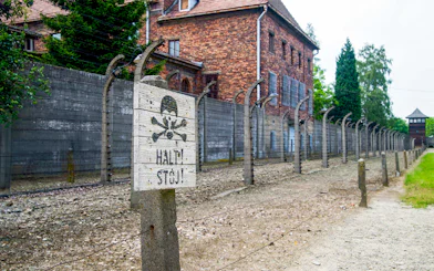 Auschwitz-Birkenau Museum fence and warning sign near Krakow bus tour.