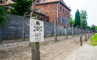 Auschwitz-Birkenau Museum fence and warning sign near Krakow bus tour.