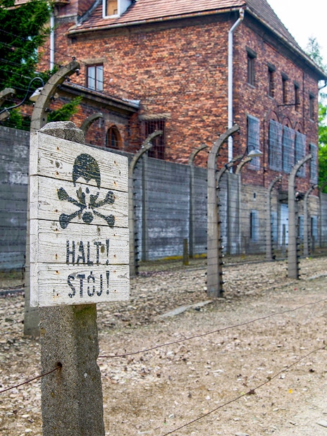Auschwitz-Birkenau Museum fence and warning sign near Krakow bus tour.