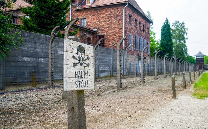 Auschwitz-Birkenau Museum fence and warning sign near Krakow bus tour.