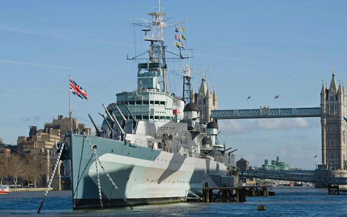 HMS Belfast moored on the River Thames with Tower Bridge in the background, London.