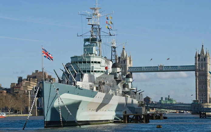 HMS Belfast moored on the River Thames with Tower Bridge in the background, London.