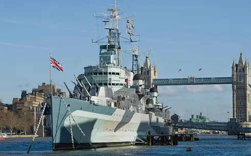 HMS Belfast moored on the River Thames with Tower Bridge in the background, London.
