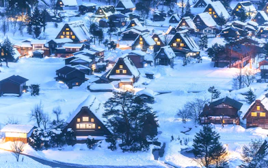 Traditional gassho-zukuri houses in snow-covered Shirakawa-go village, illuminated at dusk.