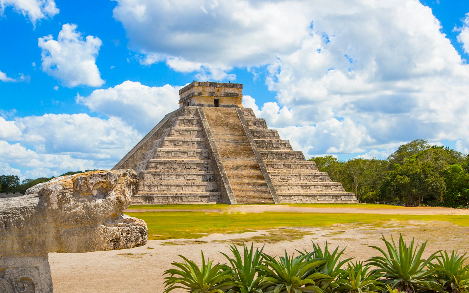 Chichen Itza's El Castillo pyramid in Yucatán, Mexico, with serpent sculpture in foreground.