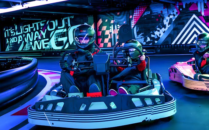Go-kart drivers racing indoors at F1® Drive London experience.