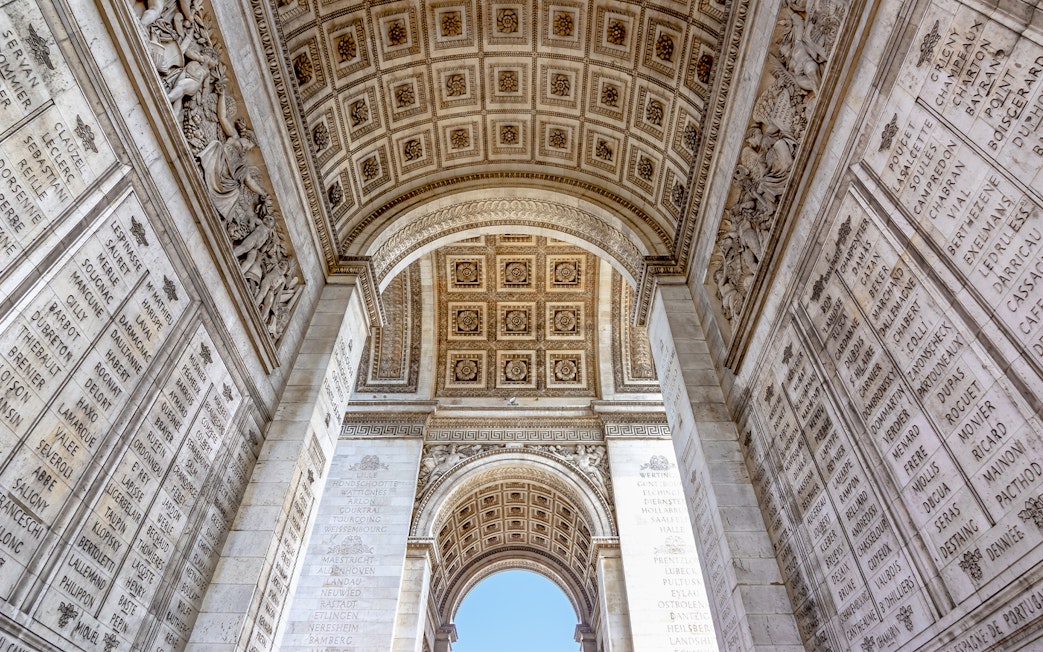 Arc de Triomphe interior with engraved names and ornate ceiling, Paris.