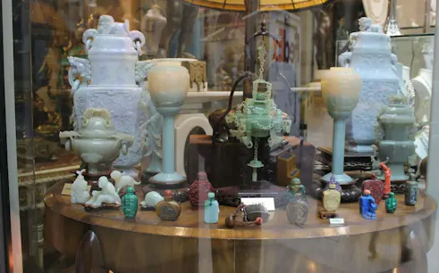 Antique jade artifacts displayed in a New York shop window, part of a self-guided city exploration game.
