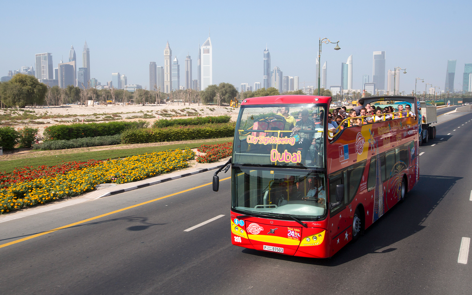 Open-top sightseeing bus in Dubai with city skyline in the background.