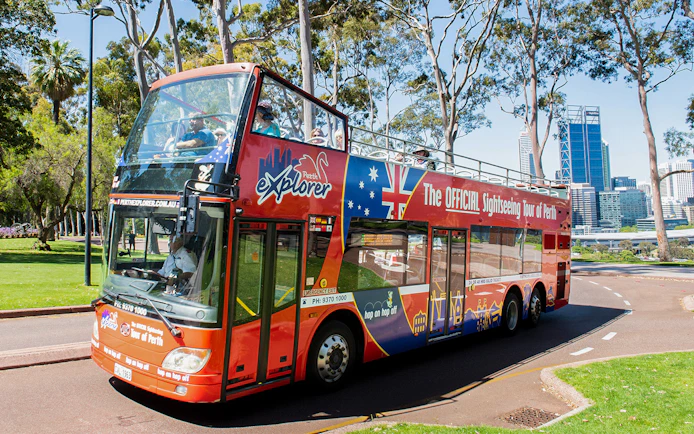 Perth sightseeing bus on tour with city skyline in background.