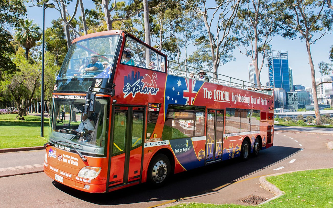 Perth sightseeing bus on tour with city skyline in background.