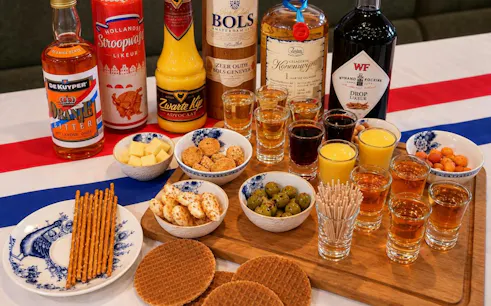 Traditional Dutch drinks and snacks, including genever, advocaat, cheese, and stroopwafels, in Amsterdam.