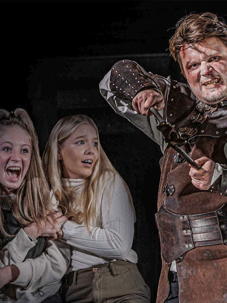 Actor in medieval costume scaring visitors at London Dungeon VIP experience.