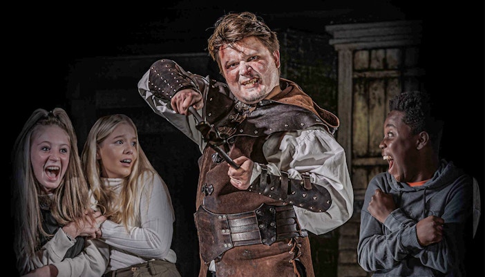 Actor in medieval costume scaring visitors at London Dungeon VIP experience.