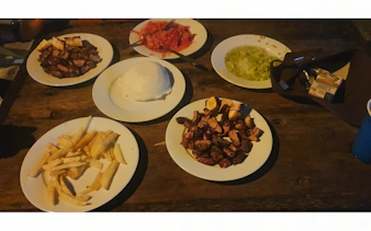 Traditional Zanzibar meal with grilled meat, fries, and local sauces on a wooden table.