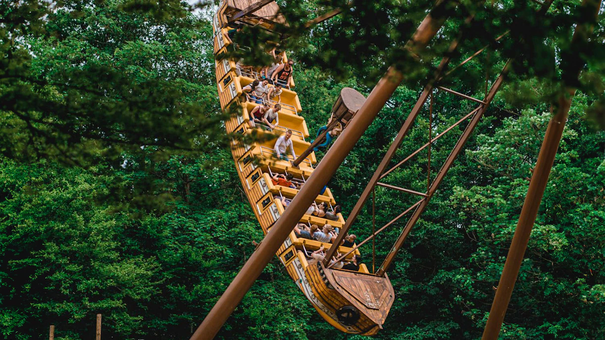 Tourists on a pirate ship ride at Bellewaerde Christmas park surrounded by trees.