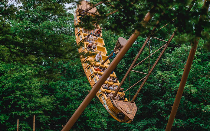 Tourists on a pirate ship ride at Bellewaerde Christmas park surrounded by trees.