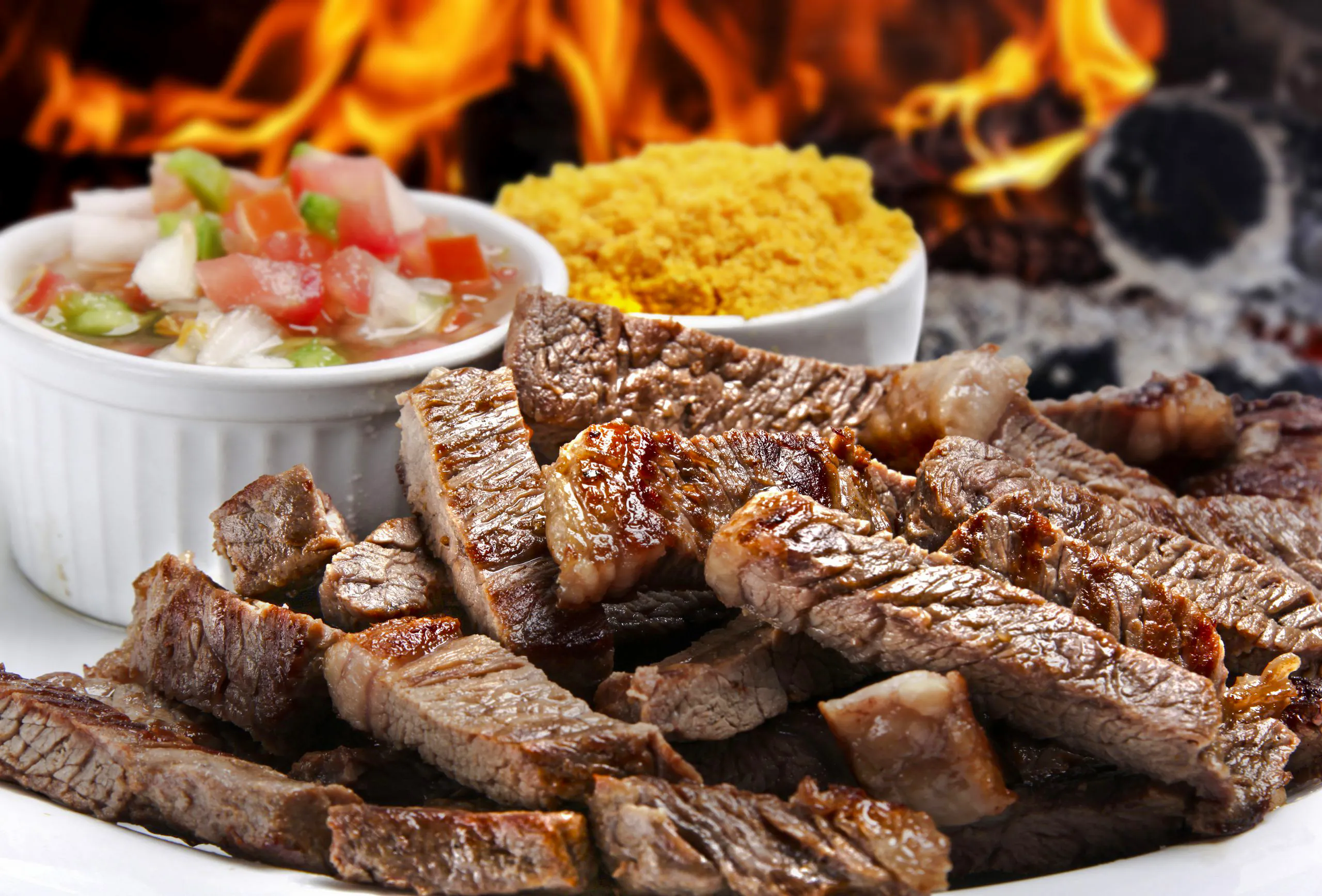 Grilled meat slices with salsa and farofa at a Brazilian steakhouse in Rio de Janeiro.