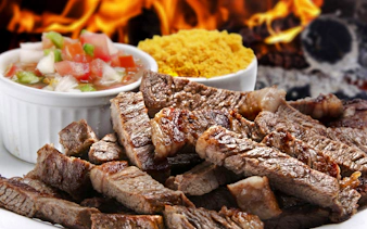 Grilled meat slices with salsa and farofa at a Brazilian steakhouse in Rio de Janeiro.