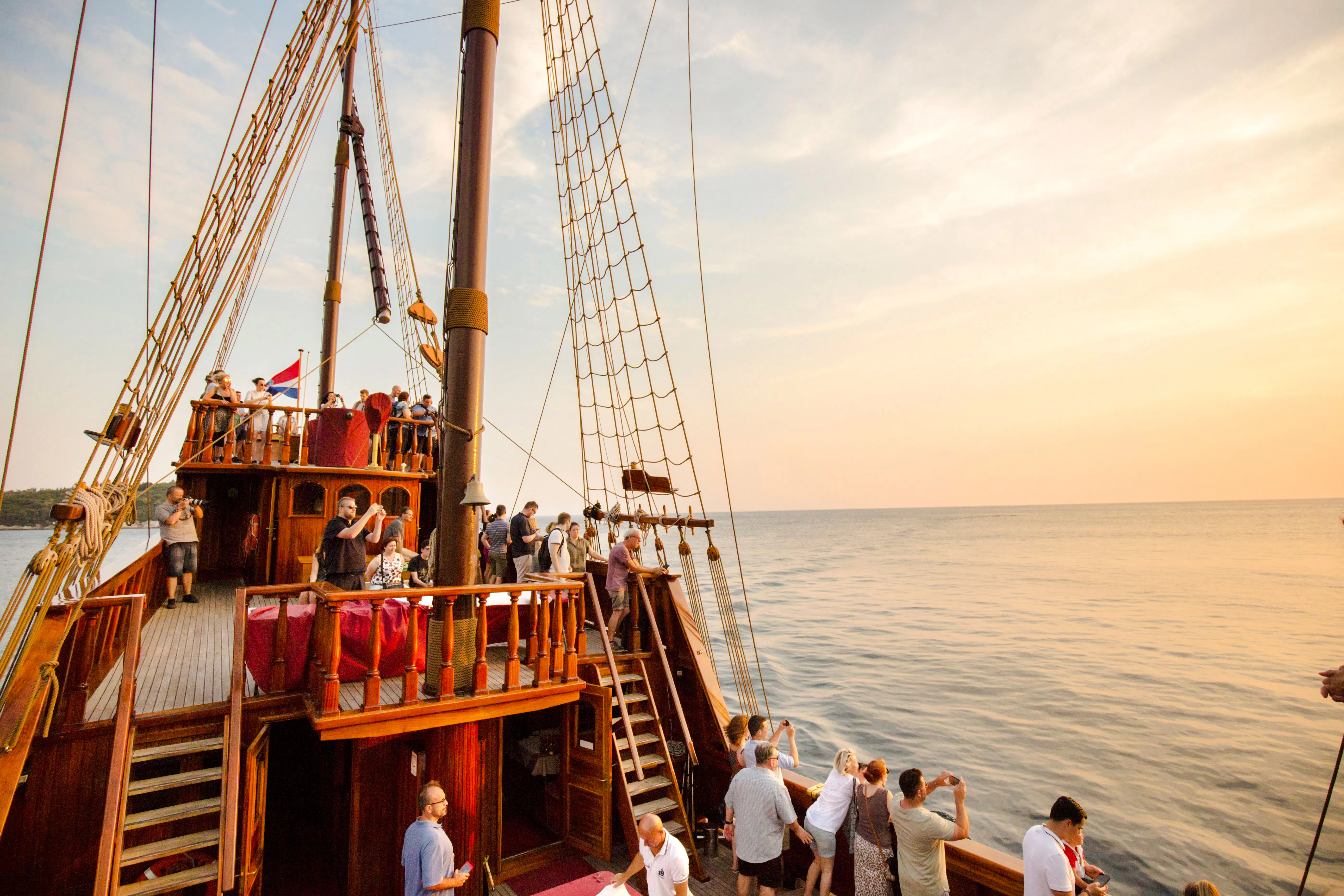 Pirate ship cruise with tourists enjoying sunset views near Old Town Dubrovnik.