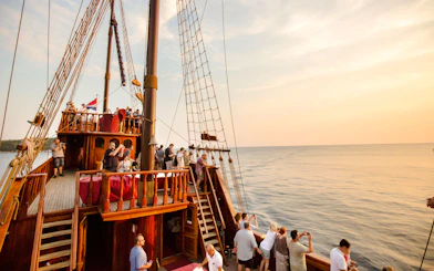 Pirate ship cruise with tourists enjoying sunset views near Old Town Dubrovnik.