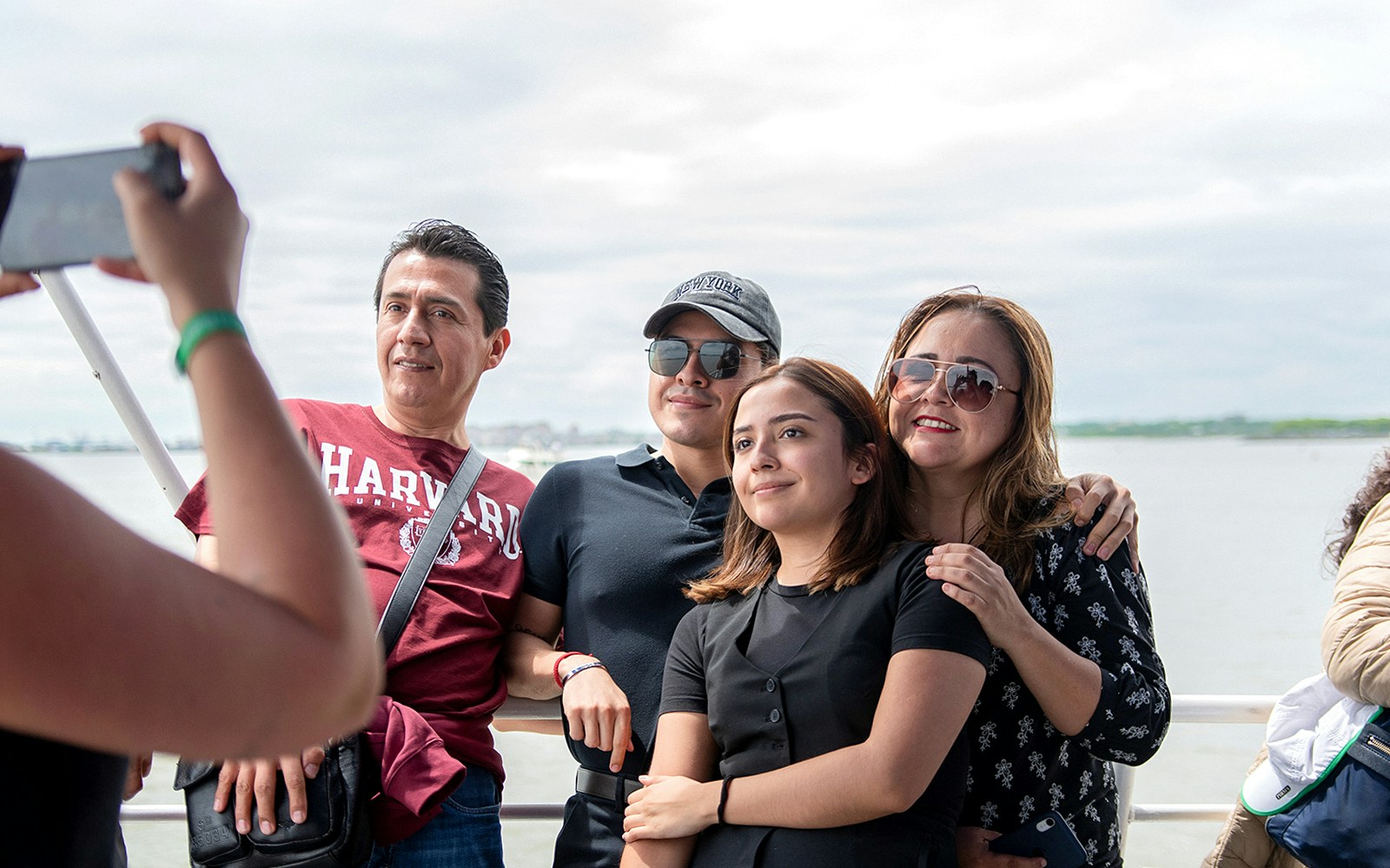 Tourist photographing Statue of Liberty from sightseeing cruise in New York City.