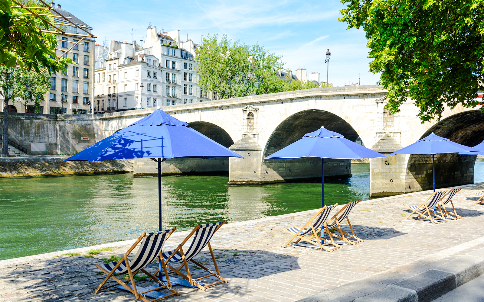 Deck chairs and blue umbrellas along the Seine River at Paris Plages.