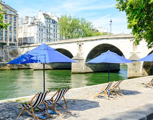 Deck chairs and blue umbrellas along the Seine River at Paris Plages.